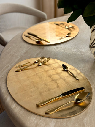 Two Art of Living Placemats in Brushed Gold on a travertine table with gold cutlery